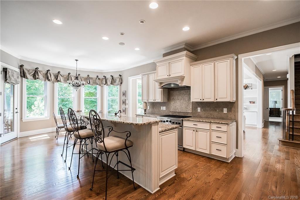 8116 Balcony Bridge Road Huntersville, NC 28078 - Photo 7 of 31 a open kitchen with stainless steel appliances granite countertop a stove top oven a dining table and chairs with wooden floor