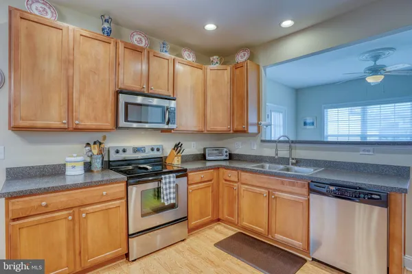 a kitchen with stainless steel appliances granite countertop a dining table chairs refrigerator and cabinets