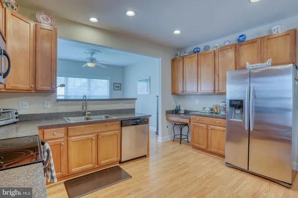 a open kitchen with stainless steel appliances granite countertop a stove a sink a microwave a dining table and chairs with wooden floor