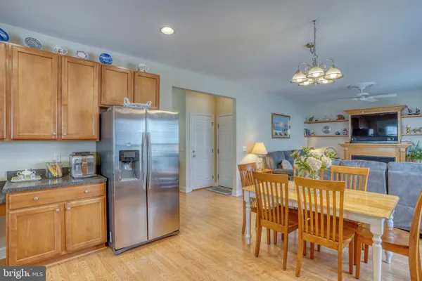 a kitchen with stainless steel appliances granite countertop a stove top oven a sink a dining table and chairs with wooden floor