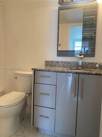 a bathroom with a granite countertop toilet sink and mirror