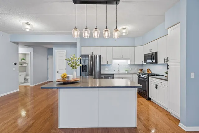 a kitchen with stainless steel appliances kitchen island granite countertop a refrigerator a stove top oven a sink and dishwasher