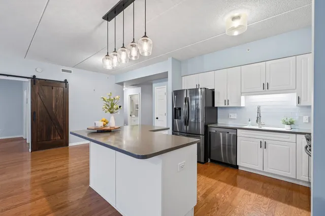 a kitchen with stainless steel appliances granite countertop a refrigerator a sink dishwasher a stove and a refrigerator with wooden floor