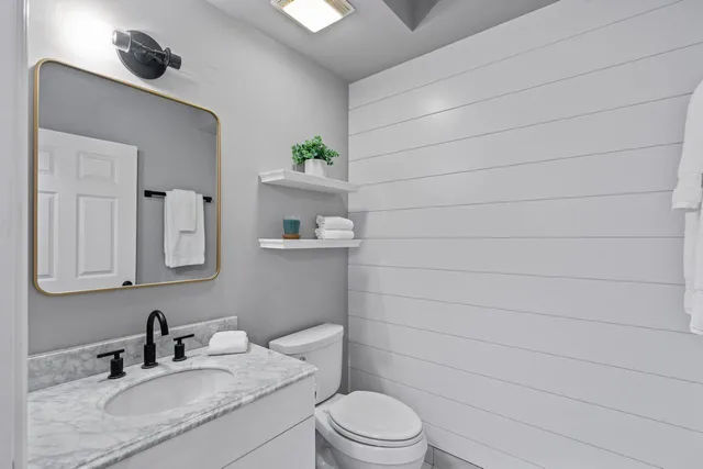 a bathroom with a granite countertop sink toilet and mirror