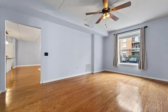 a view of an empty room with window and a kitchen