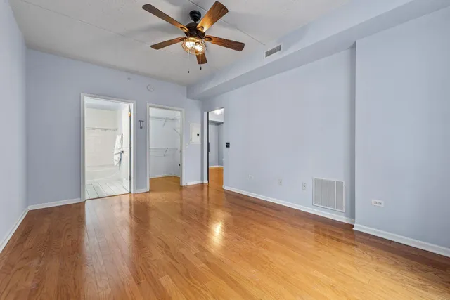 an empty room with wooden floor and a ceiling fan