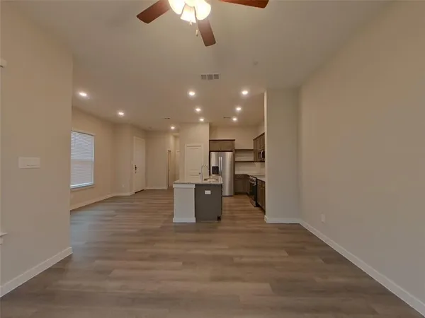 a view of kitchen and empty room with wooden floor
