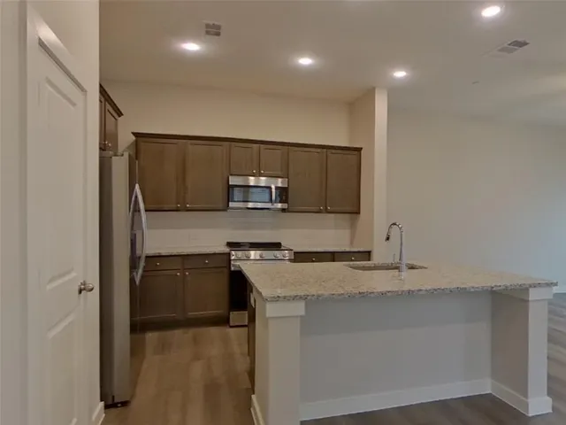 a kitchen with kitchen island granite countertop appliances cabinets and a sink