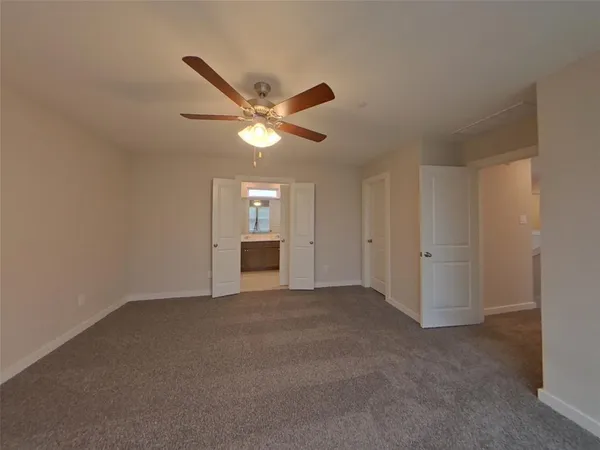an empty room with windows and ceiling fan