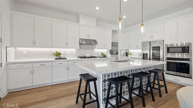 a kitchen with stainless steel appliances granite countertop a table chairs stove and white cabinets