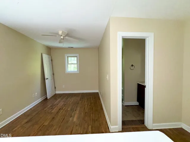 a view of an empty room with window and wooden floor