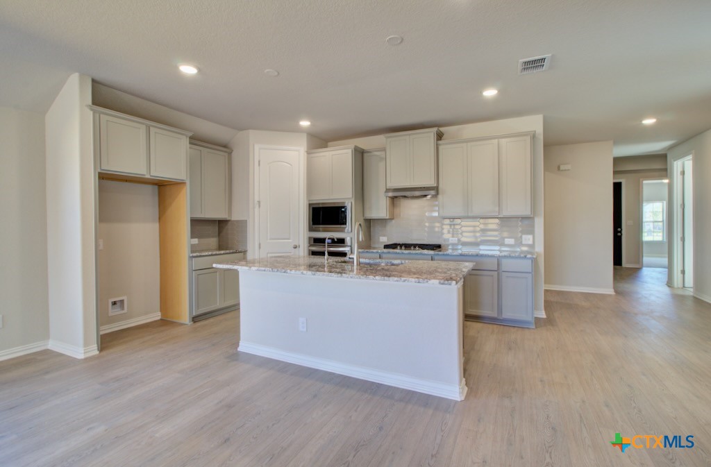 2118 Shepard Street Seguin, TX 78155 - Photo 2 of 24 a kitchen with kitchen island a sink a stove a refrigerator and white cabinets
