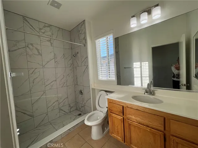 a bathroom with a granite countertop sink a toilet a mirror and shower