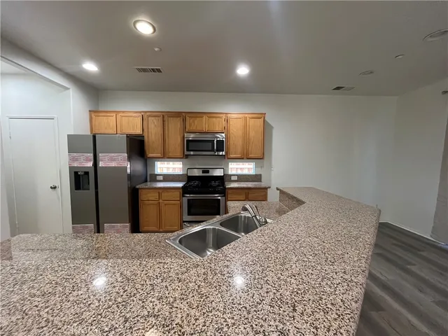 a kitchen with stainless steel appliances kitchen island granite countertop a refrigerator and a sink