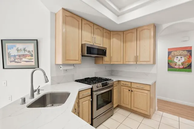 a kitchen with white cabinets a sink and a stove with wooden floor