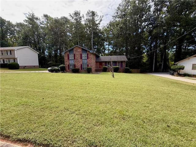 a yellow house with a big yard and large trees