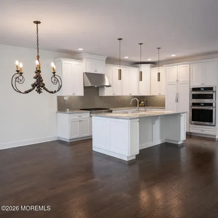 a kitchen with stainless steel appliances granite countertop a sink a stove and a wooden floor