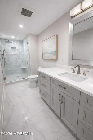 a bathroom with a granite countertop sink mirror bathtub and toilet