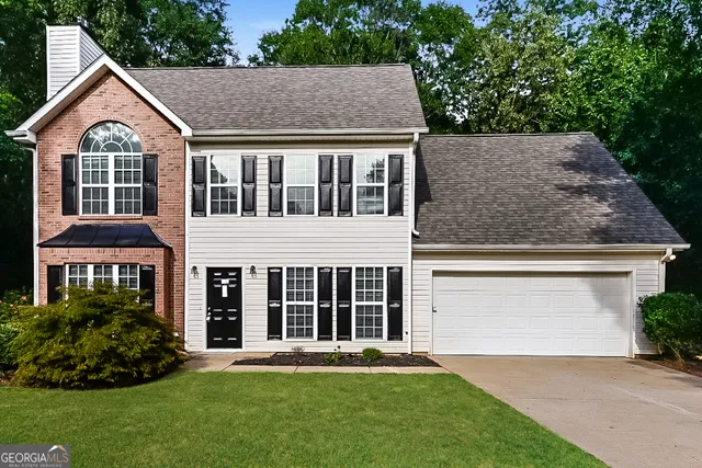 a view of a yard in front of a house with plants and large tree