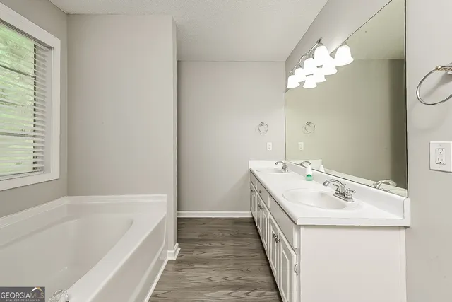 a bathroom with a tub sink and mirror
