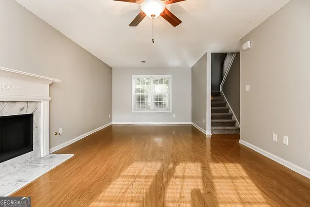 a view of an empty room with wooden floor fireplace and a window