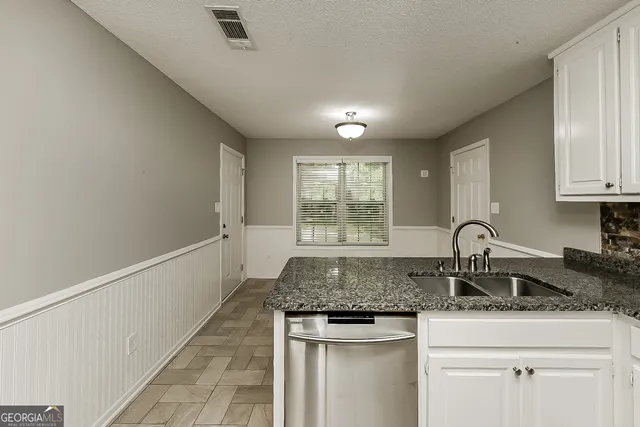 a kitchen with granite countertop a sink and cabinets