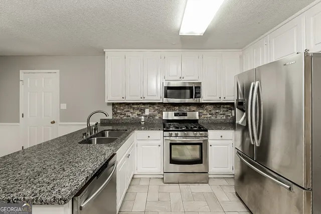 a kitchen with stainless steel appliances granite countertop a sink stove and refrigerator