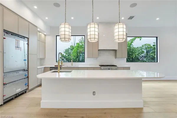 a large kitchen with kitchen island white cabinets and a chandelier