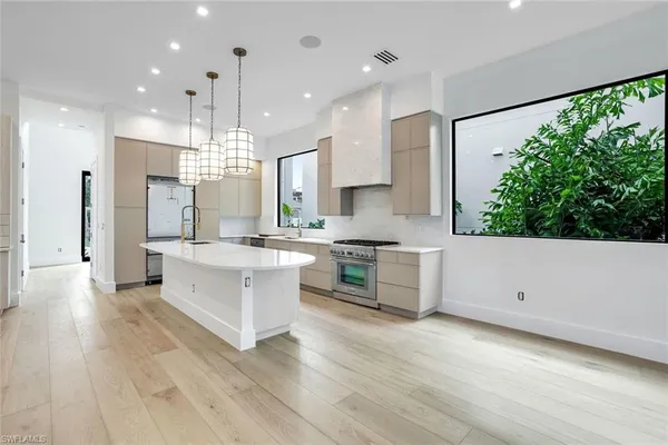 a large kitchen with kitchen island white cabinets and stainless steel appliances