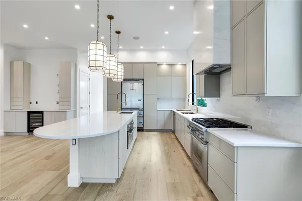 a kitchen with stainless steel appliances kitchen island granite countertop a stove a sink a refrigerator and white cabinets with wooden floor