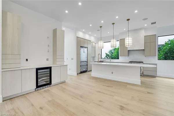 a view of kitchen with stainless steel appliances granite countertop a stove a sink a refrigerator and white cabinets with wooden floor
