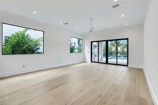 an empty room with wooden floor and windows