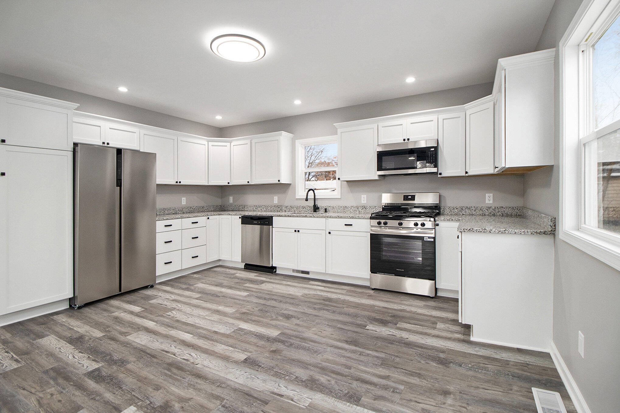 4124 Liverpool Road Lake Station, IN 46405 - Photo 6 of 18 a kitchen with granite countertop a refrigerator stove a sink and dishwasher with wooden floor