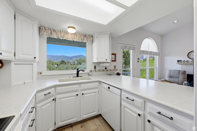 3766 Cardiff Circle Bountiful, UT 84010 - Photo 11 of 46 Kitchen featuring white cabinetry, light-toned countertops, a built-in dishwasher, and a window with mountain scenery