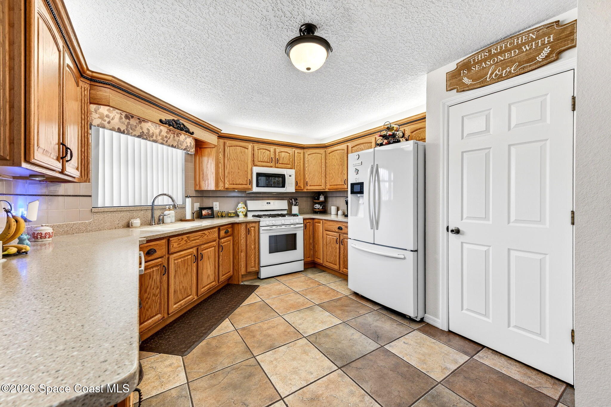 3969 Ridgewood Drive Titusville, FL 32796 - Photo 14 of 34 a kitchen with stainless steel appliances granite countertop a refrigerator oven a sink dishwasher and white cabinets with wooden floor