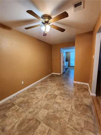 an empty room with chandelier fan and windows