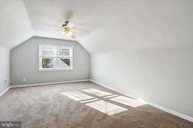 an empty room with windows and ceiling fan