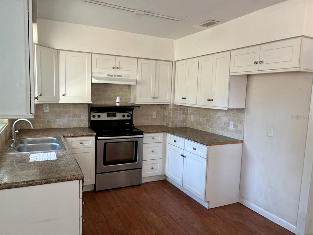 264 14th Street Northwest Largo, FL 33770 - Photo 5 of 12 a kitchen with granite countertop white cabinets and stainless steel appliances
