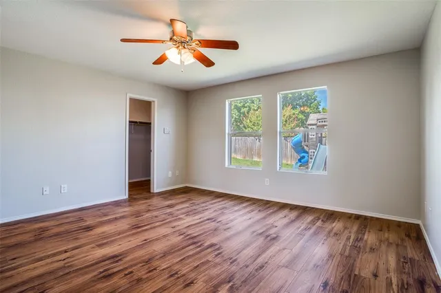 a view of an empty room with window and wooden floor