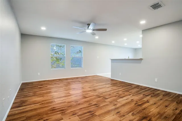 an empty room with kitchen view and wooden floor
