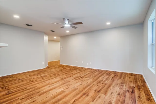 an empty room with wooden floor and fan