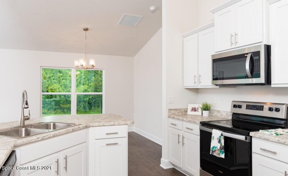 318 Trilby Road Southwest Palm Bay, FL 32908 - Photo 5 of 17 a kitchen with stainless steel appliances granite countertop a sink a stove a microwave and wooden cabinets
