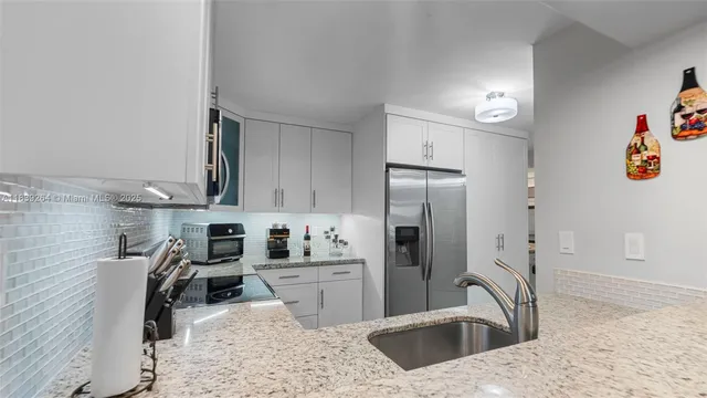 a kitchen with stainless steel appliances kitchen island granite countertop a sink stove and refrigerator