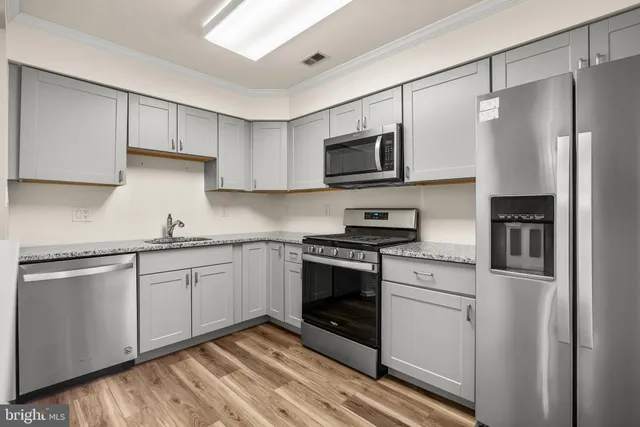 a kitchen with stainless steel appliances granite countertop a stove a sink and a refrigerator