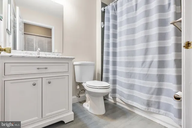 a bathroom with a granite countertop toilet a sink and a mirror