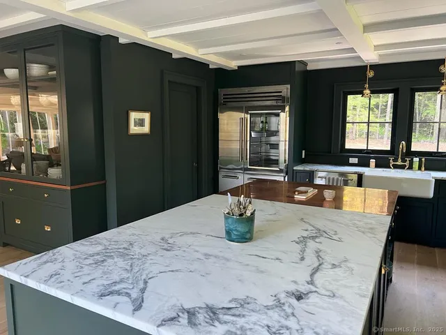 a dining hall with granite countertop a refrigerator a sink a dining table and chairs