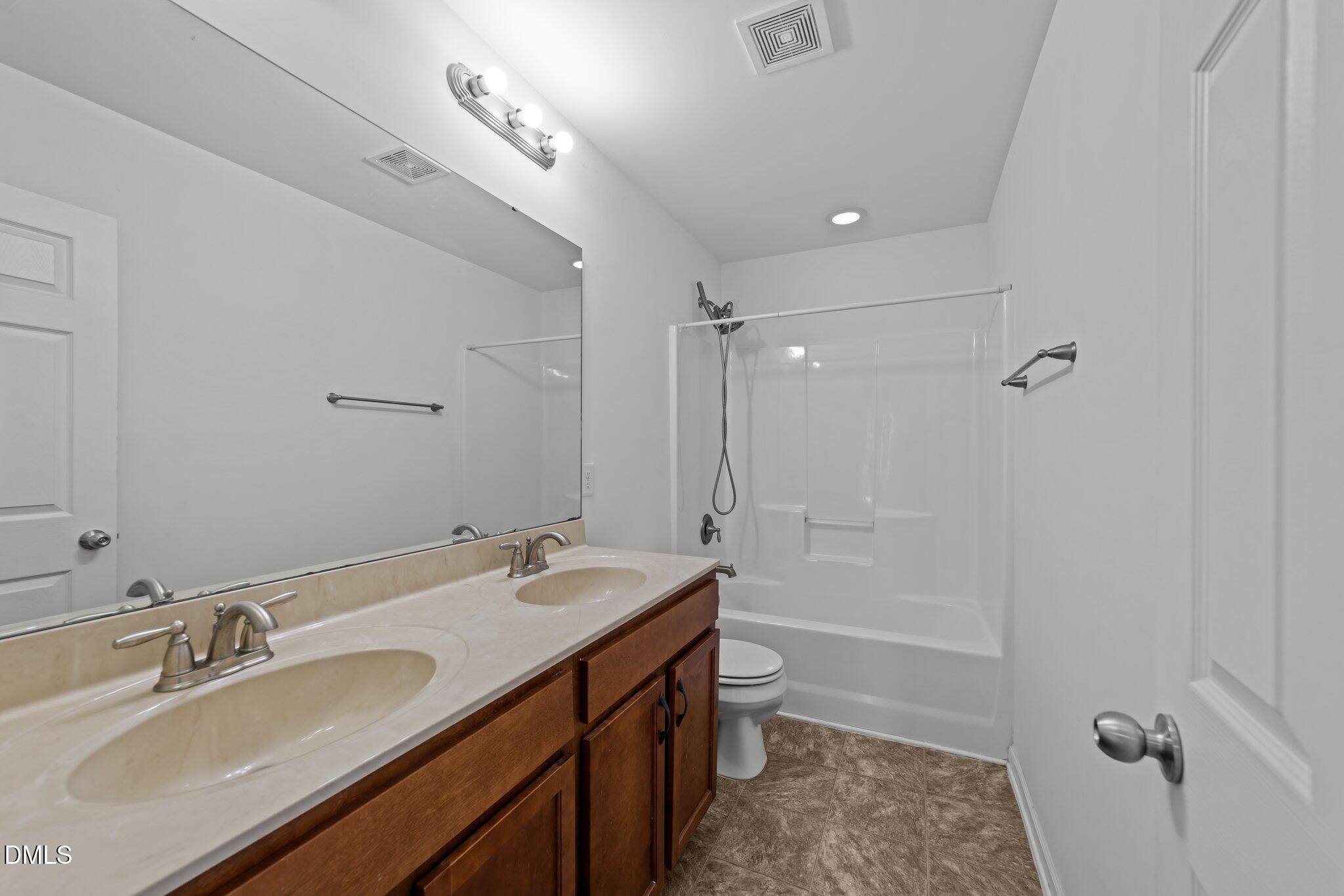 1445 Lombar Street Raleigh, NC 27610 - Photo 15 of 20 a bathroom with a double vanity sink toilet mirror and bathtub
