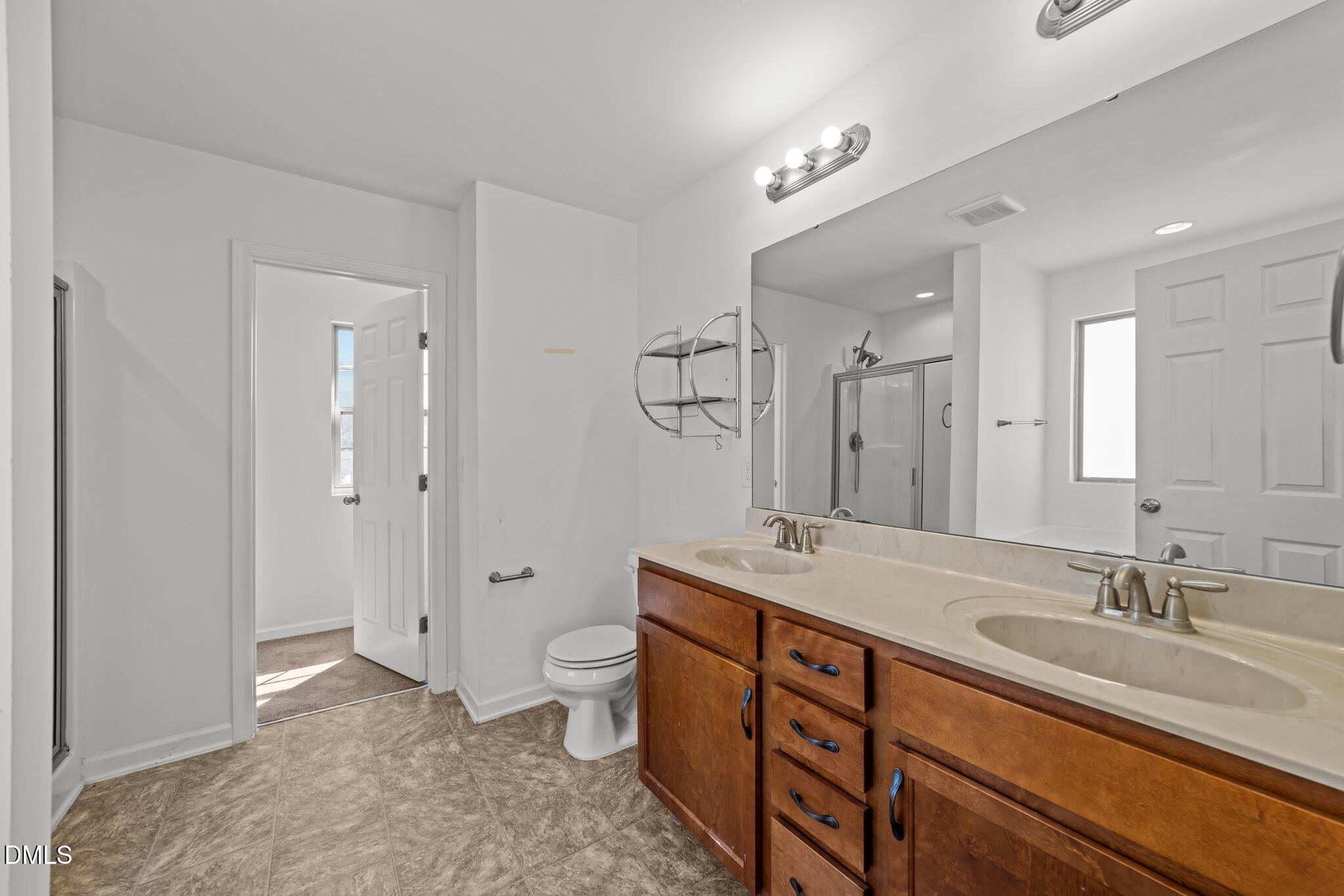 1445 Lombar Street Raleigh, NC 27610 - Photo 18 of 20 a spacious bathroom with a granite countertop sink a toilet and a shower