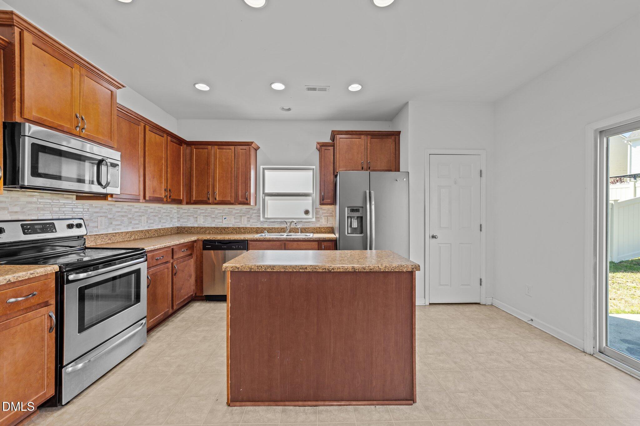 1445 Lombar Street Raleigh, NC 27610 - Photo 7 of 20 a kitchen with stainless steel appliances granite countertop a stove top oven a sink and a refrigerator