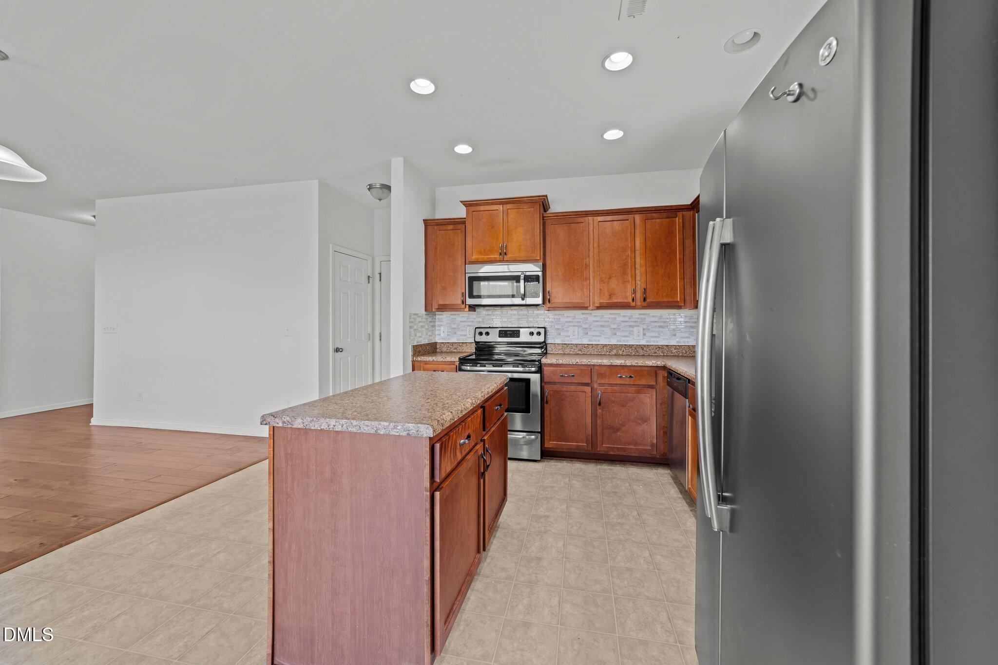 1445 Lombar Street Raleigh, NC 27610 - Photo 8 of 20 a kitchen with stainless steel appliances granite countertop a stove a sink and a refrigerator